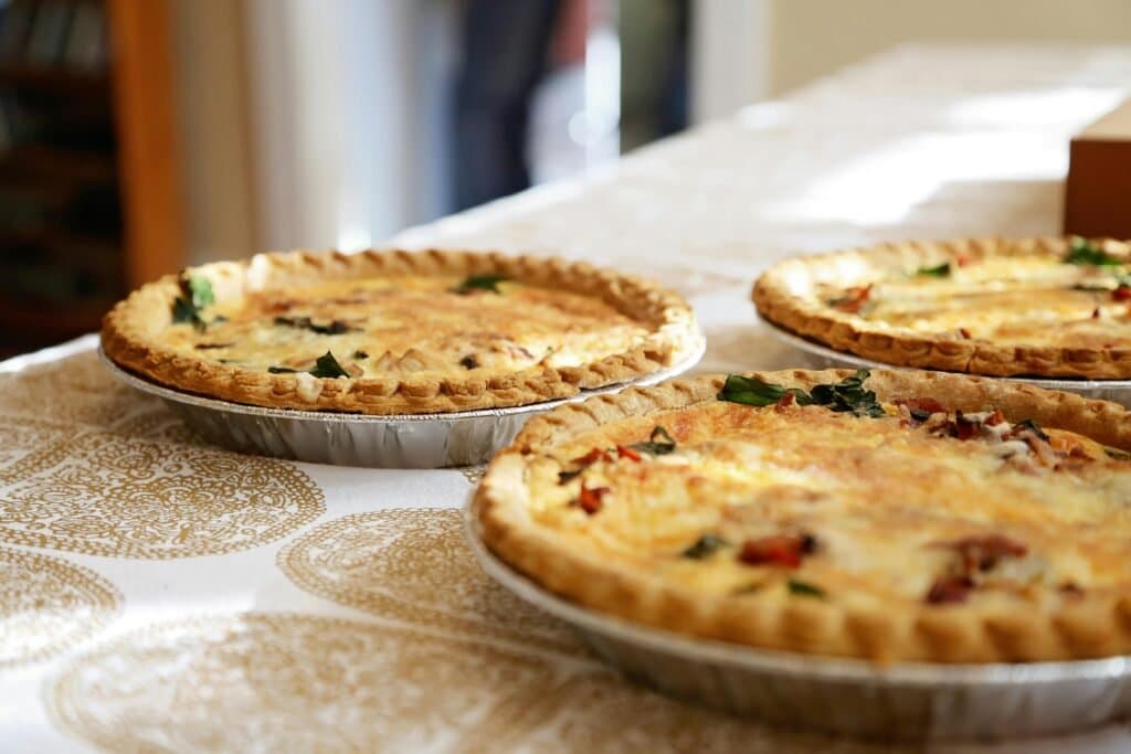 A golden-brown baked bacon and mushroom paptert in a white ovenproof dish, ready to be served.
