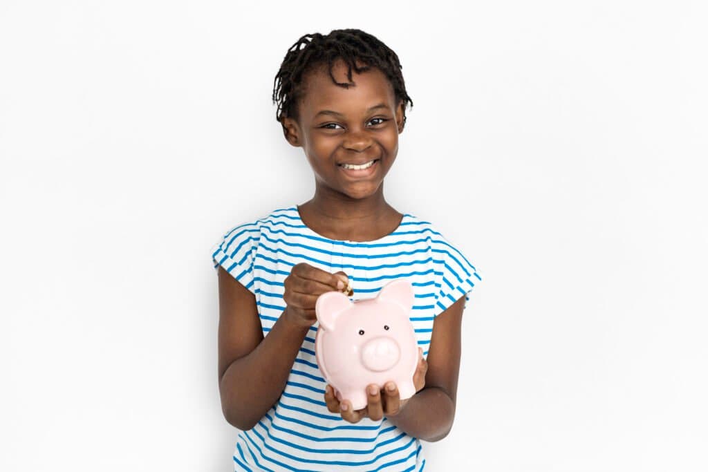 A-child-learning-about-teaching-kids-about-money-by-putting-a-coin-in-a-piggy-bank